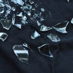 Specchio rotto su un pavimento, avviso sulla sfortuna e smaltimento corretto.